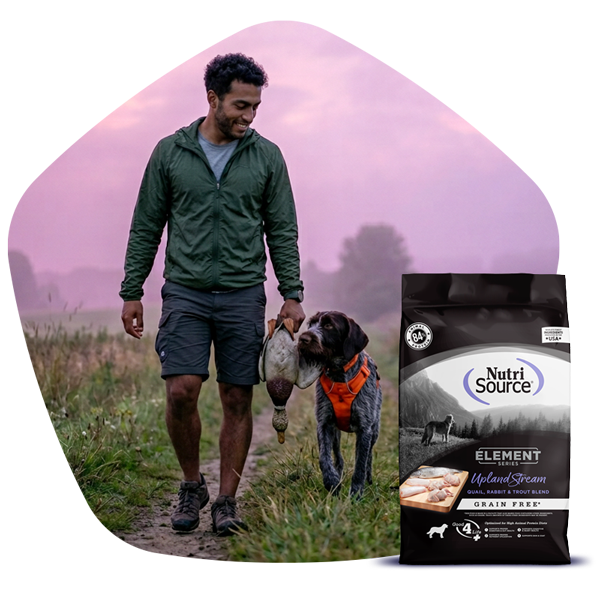 Man walking a dog in a field, NutriSource® Element Series dog food bag in the foreground