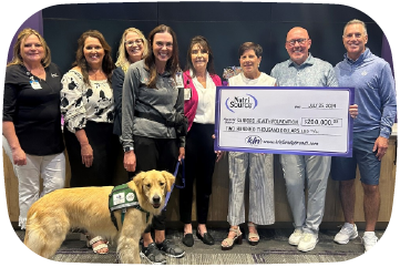 Group of people holding a large check with a dog standing next to them