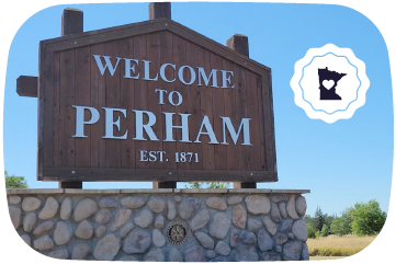 Welcome sign to Perham with a stone base and clear blue sky