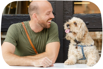 Man sitting next to a dog outdoors