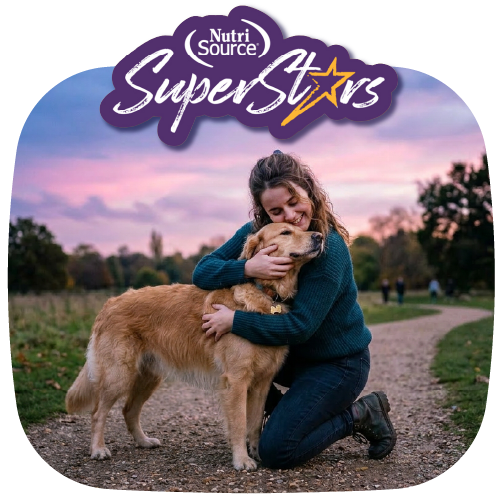Woman hugging a dog at sunset with NutriSource® Super Stars logo above